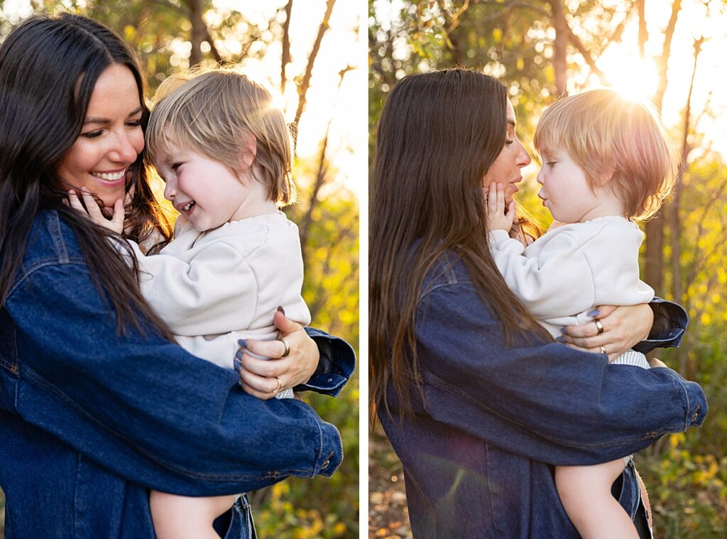 Mom in a denim jacket holding her toddler son in the woods at golden hour, faces close with soft backlight.