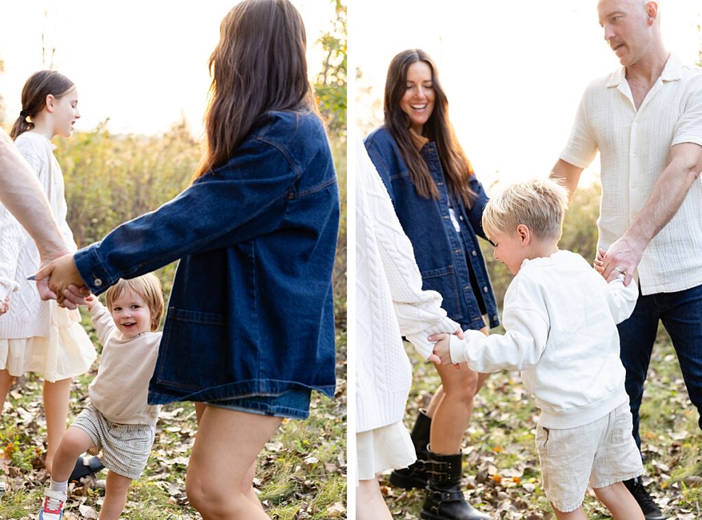 Family members holding hands and spinning in a circle on a leaf-covered field during a playful outdoor shoot.