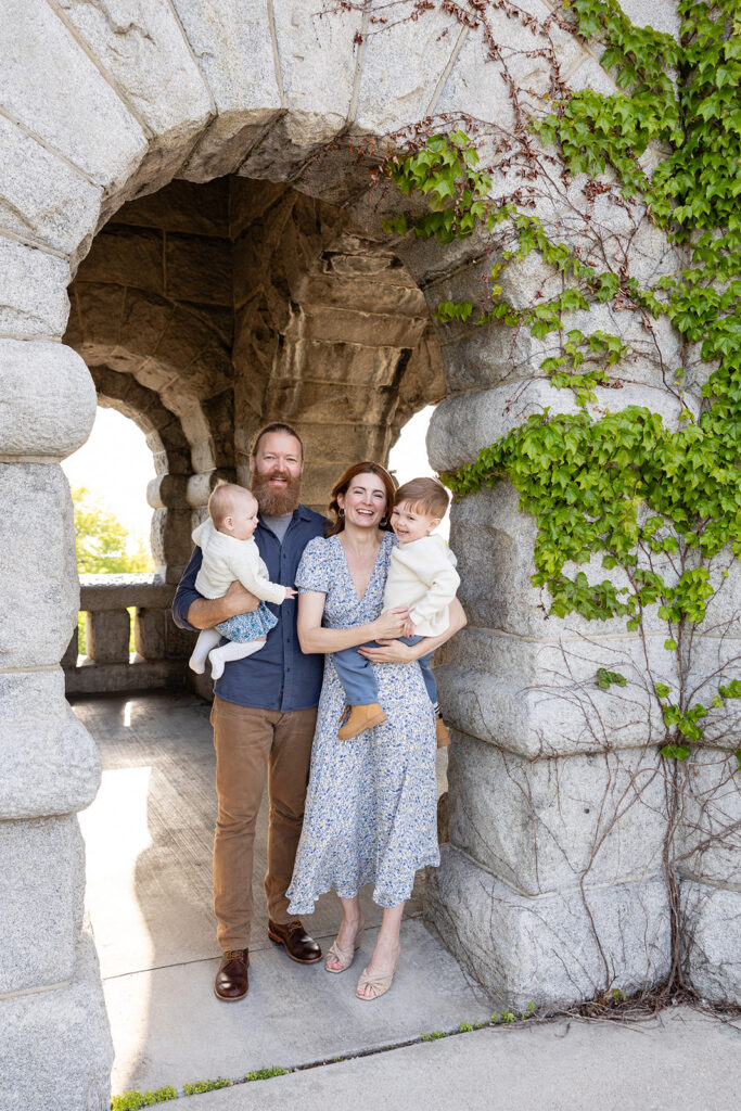 Family of four standing beneath a stone archway covered in ivy at Lincoln Park Nature Boardwalk.