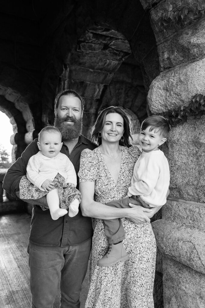 Black and white family portrait beneath a stone archway at Lincoln Park Nature Boardwalk in Chicago.