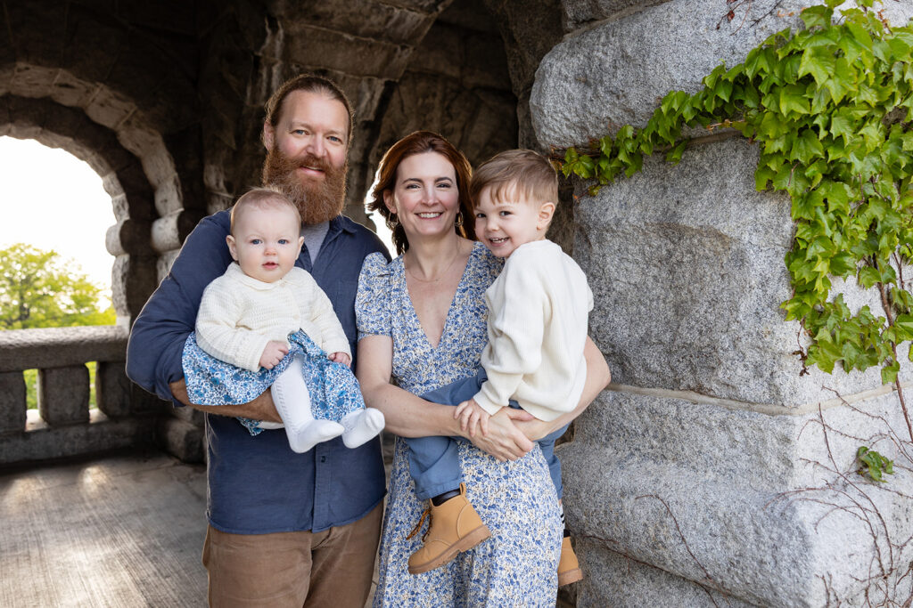 Family portrait with two young children beneath the stone pavilion at Lincoln Park Nature Boardwalk.