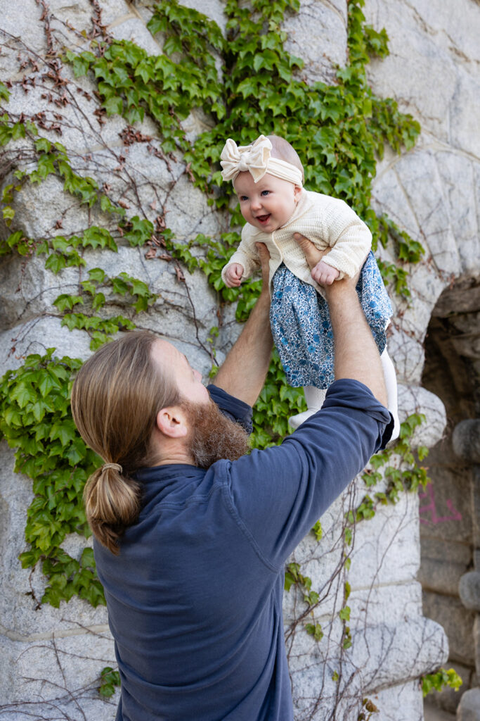 Father lifting his baby daughter into the air during a family session at Lincoln Park Nature Boardwalk.