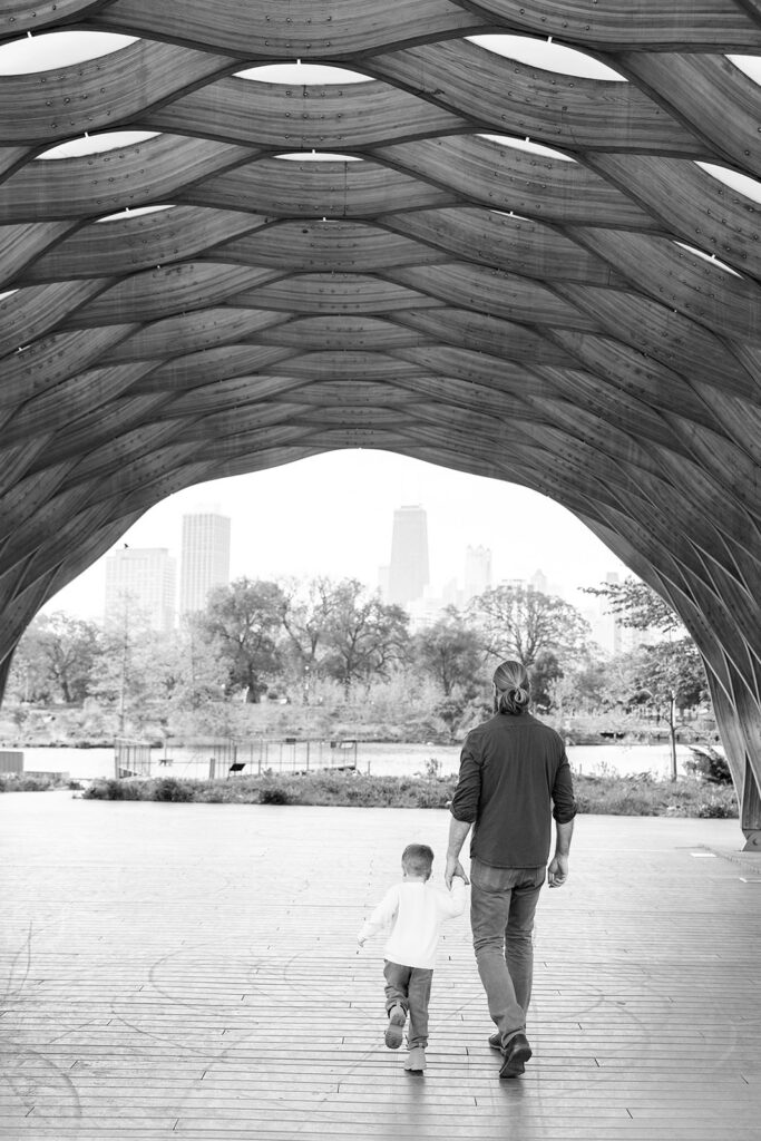 Black and white photo of father and son walking away together beneath the pavilion at Lincoln Park Nature Boardwalk