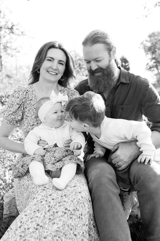 Black and white family portrait sitting together near the pond during a spring session at Lincoln Park Nature Boardwalk