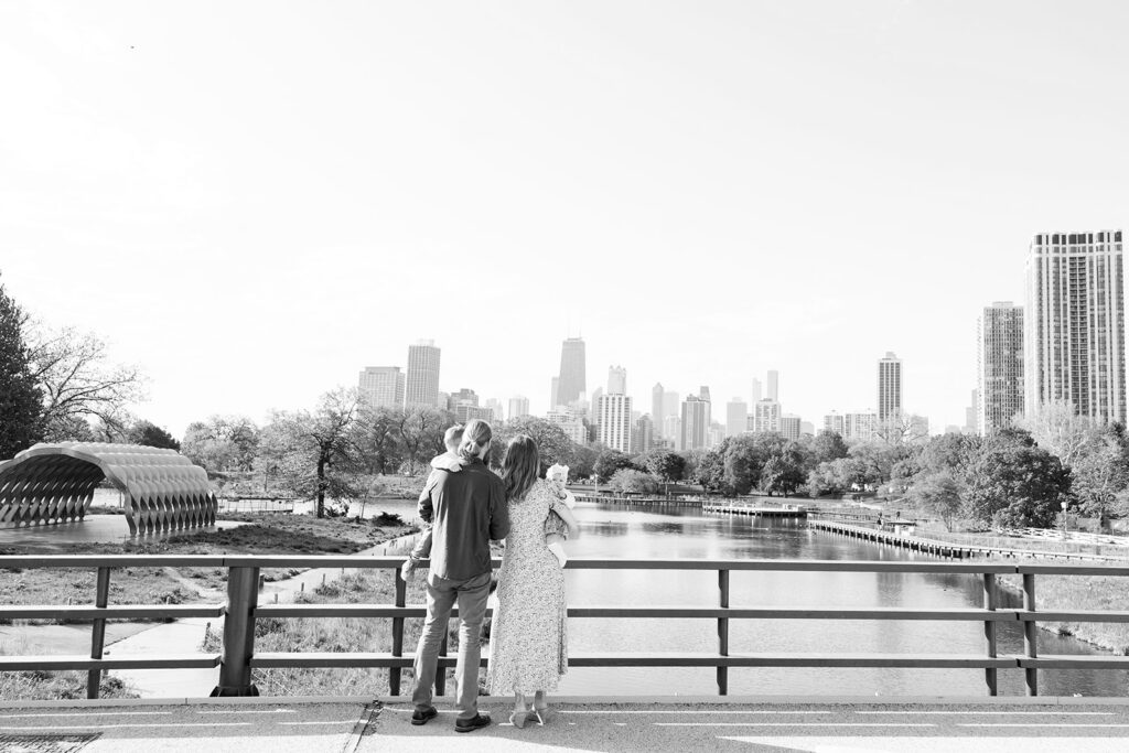 Black and white family portrait overlooking the water with the Chicago skyline from a bridge near Lincoln Park Nature Boardwalk