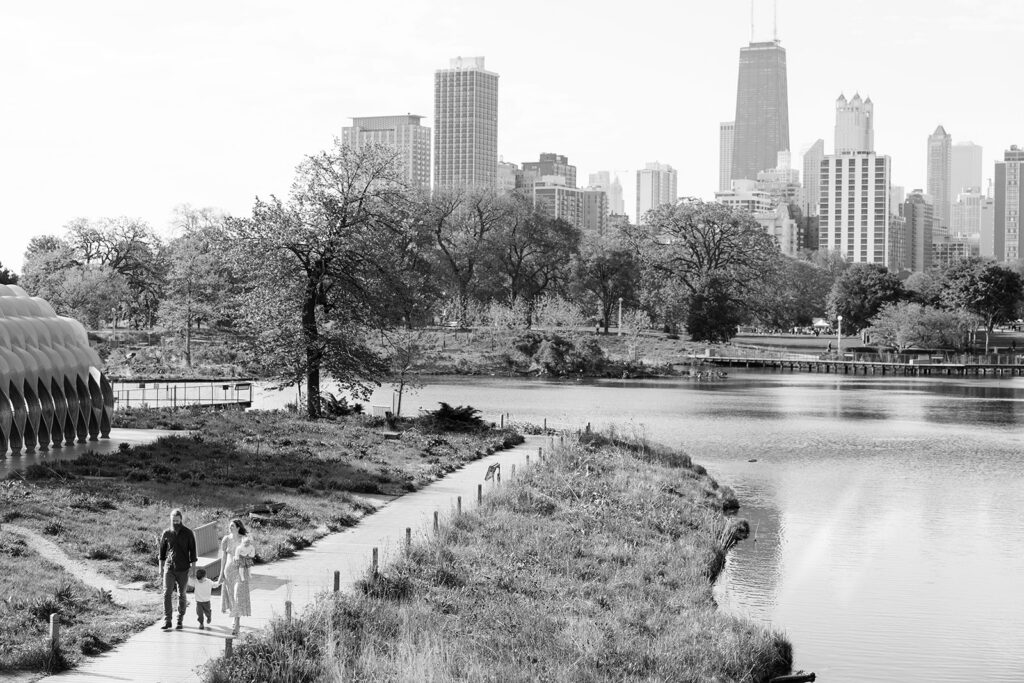 Family walking along the Lincoln Park Nature Boardwalk in Chicago with the city skyline and pond in the background